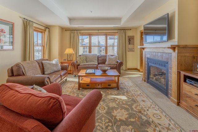 carpeted living room with a tray ceiling and a tile fireplace