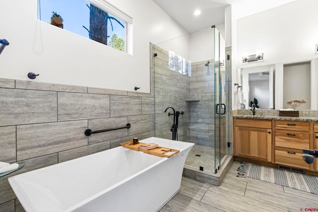 bathroom featuring shower with separate bathtub, vanity, and tile walls