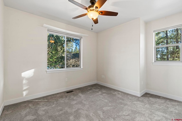 carpeted spare room featuring a wealth of natural light and ceiling fan