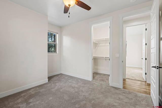 unfurnished bedroom featuring ceiling fan, a walk in closet, light carpet, and a closet