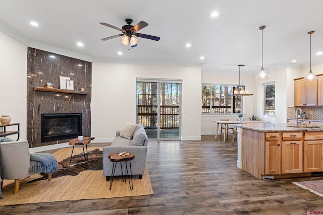 living room featuring ceiling fan, a healthy amount of sunlight, sink, and a high end fireplace