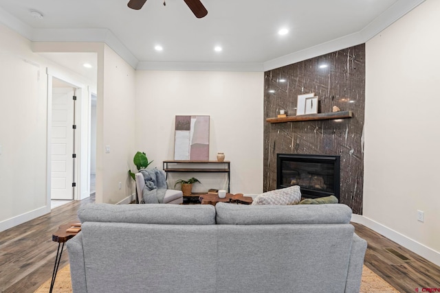 living room with a premium fireplace, ceiling fan, wood-type flooring, and ornamental molding