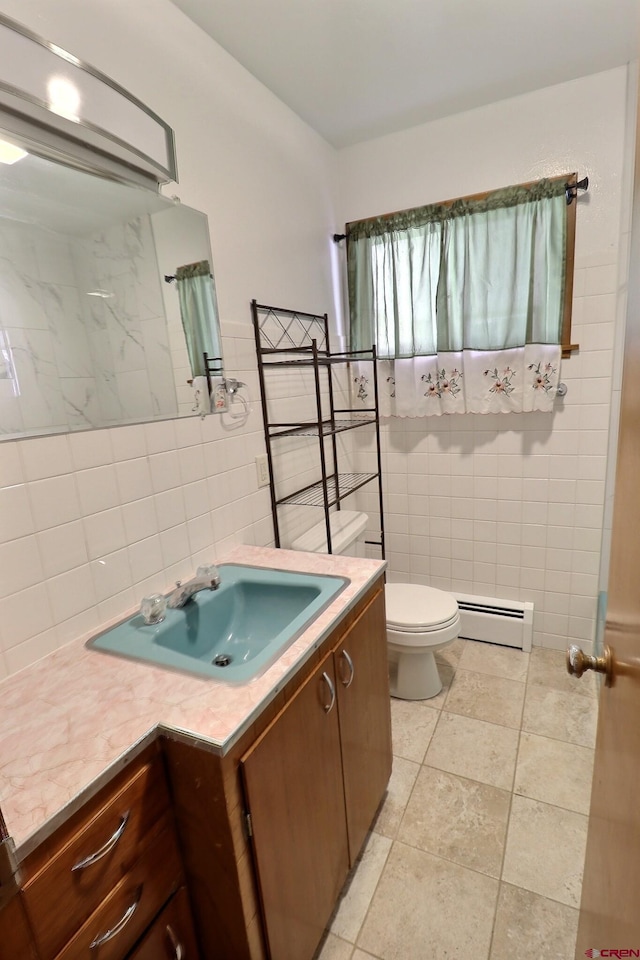 bathroom featuring vanity, toilet, baseboard heating, and tile walls