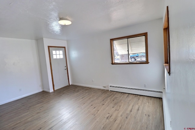 foyer with a textured ceiling, baseboard heating, a wealth of natural light, and light hardwood / wood-style flooring