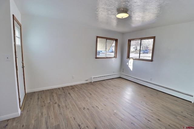 unfurnished room with light hardwood / wood-style flooring, a textured ceiling, and a baseboard heating unit