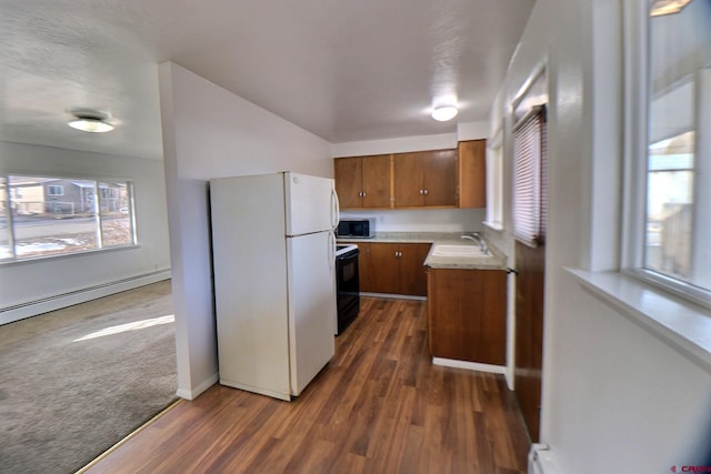 kitchen with black electric range oven, dark wood-type flooring, a baseboard heating unit, white refrigerator, and sink