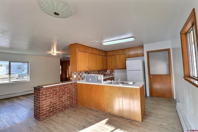 kitchen with light hardwood / wood-style floors, kitchen peninsula, and a baseboard heating unit