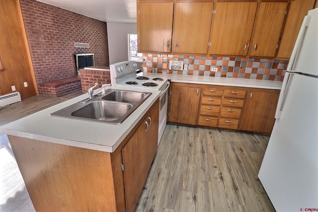 kitchen with kitchen peninsula, light wood-type flooring, brick wall, white appliances, and sink