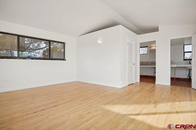 empty room featuring a wealth of natural light, light hardwood / wood-style flooring, and vaulted ceiling