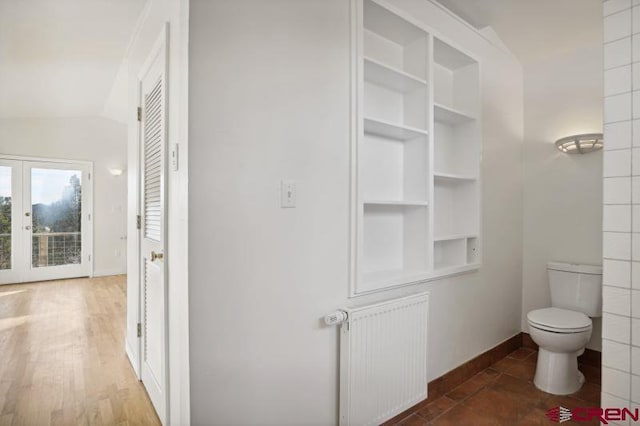 bathroom featuring french doors, wood-type flooring, radiator heating unit, toilet, and lofted ceiling