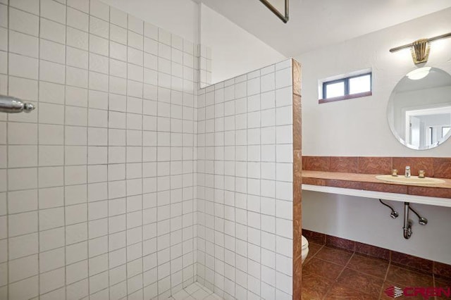 bathroom featuring tiled shower, tile patterned flooring, toilet, and sink