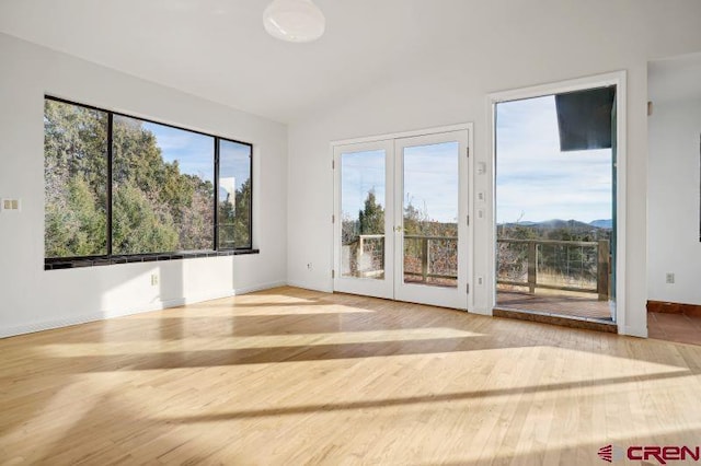 spare room with vaulted ceiling, hardwood / wood-style floors, a healthy amount of sunlight, and french doors