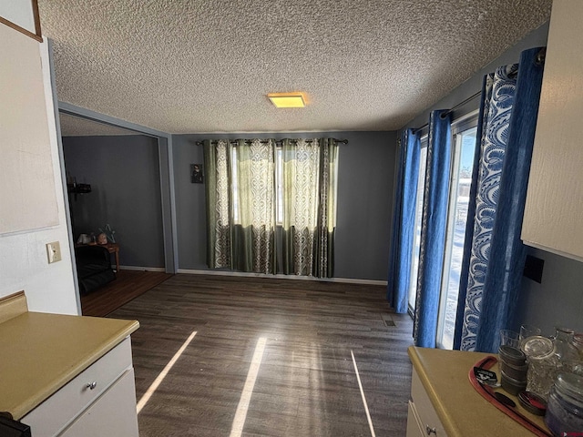 unfurnished living room featuring dark wood-type flooring and a textured ceiling