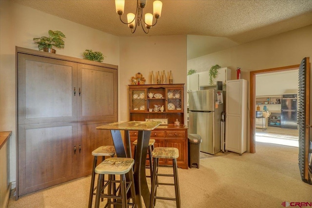 dining space with a textured ceiling, light colored carpet, an inviting chandelier, and bar