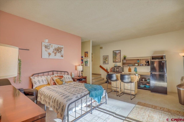 bedroom with stainless steel refrigerator, light carpet, and a textured ceiling