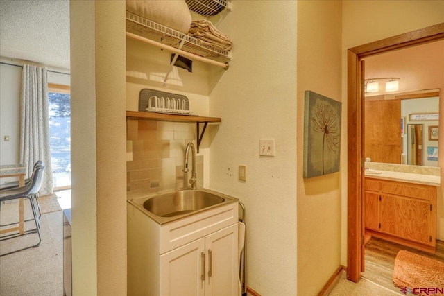 washroom with a textured ceiling, sink, and light hardwood / wood-style flooring