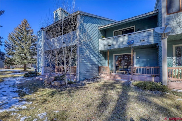 rear view of property featuring a balcony and a porch