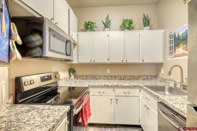 kitchen with light stone countertops, sink, white cabinets, and stainless steel appliances