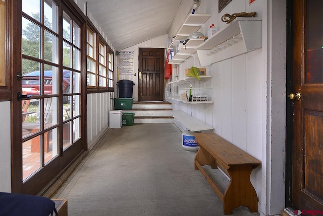 mudroom featuring concrete flooring, wooden walls, vaulted ceiling, and a healthy amount of sunlight