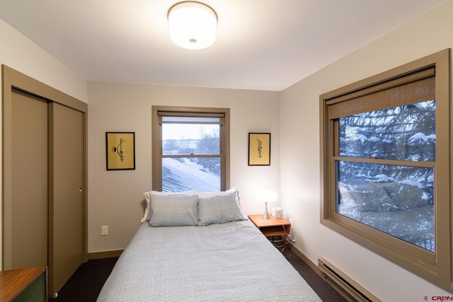 bedroom featuring dark colored carpet, a closet, and baseboard heating