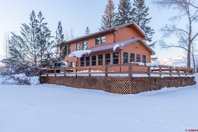 snow covered back of property featuring a deck