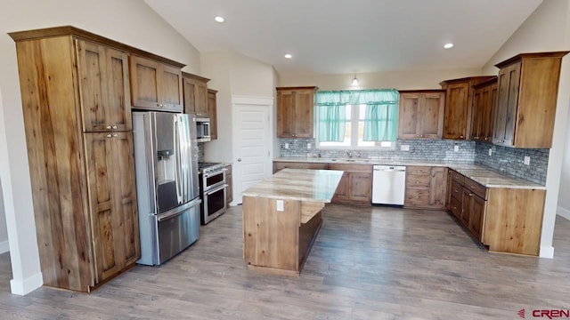 kitchen with a center island, lofted ceiling, sink, light wood-type flooring, and appliances with stainless steel finishes