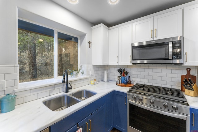 kitchen featuring appliances with stainless steel finishes, backsplash, sink, blue cabinetry, and white cabinets