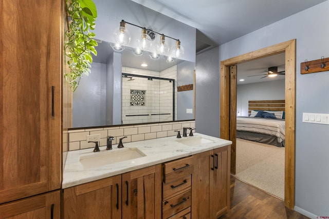 bathroom with vanity, hardwood / wood-style flooring, decorative backsplash, ceiling fan, and a shower with shower door