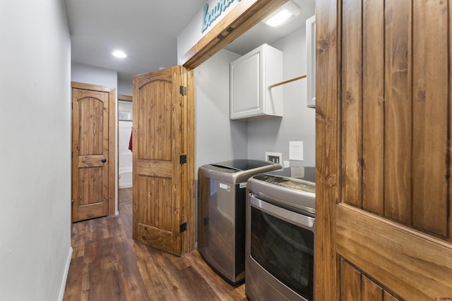 clothes washing area with washer and dryer, dark hardwood / wood-style flooring, and cabinets