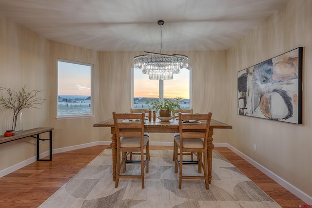 dining space with light wood-type flooring, an inviting chandelier, and plenty of natural light