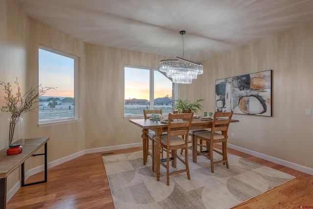 dining area featuring light wood-type flooring and an inviting chandelier