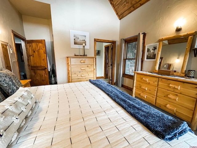 bedroom featuring light tile patterned floors, high vaulted ceiling, and ensuite bath