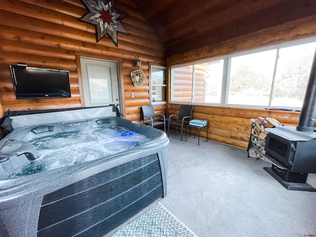 sunroom with a wood stove, a jacuzzi, and lofted ceiling