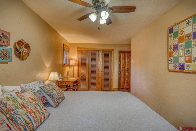 carpeted bedroom featuring ceiling fan, a textured ceiling, and a closet