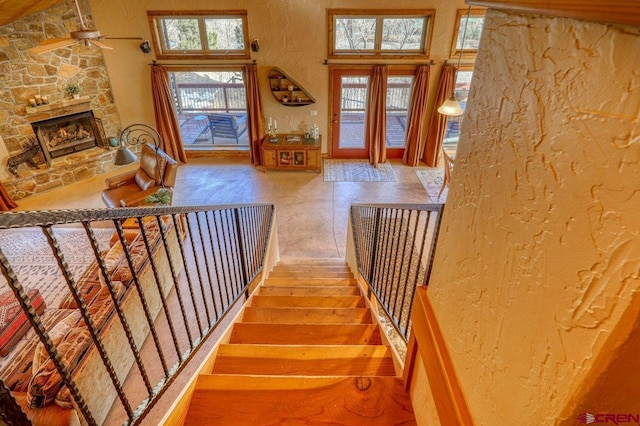 stairs with hardwood / wood-style flooring, ceiling fan, and a fireplace