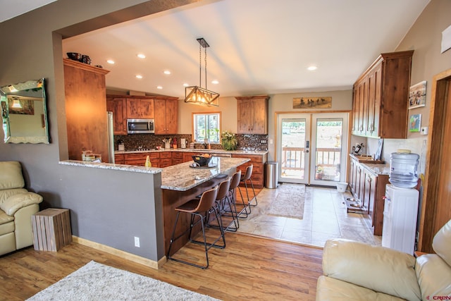 kitchen with a kitchen breakfast bar, light hardwood / wood-style floors, kitchen peninsula, and stainless steel appliances