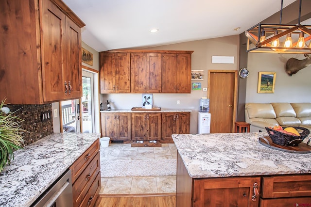 kitchen with pendant lighting, dishwasher, vaulted ceiling, light stone countertops, and light hardwood / wood-style floors