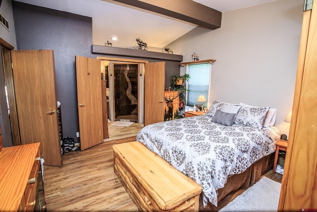 bedroom with vaulted ceiling with beams and light wood-type flooring