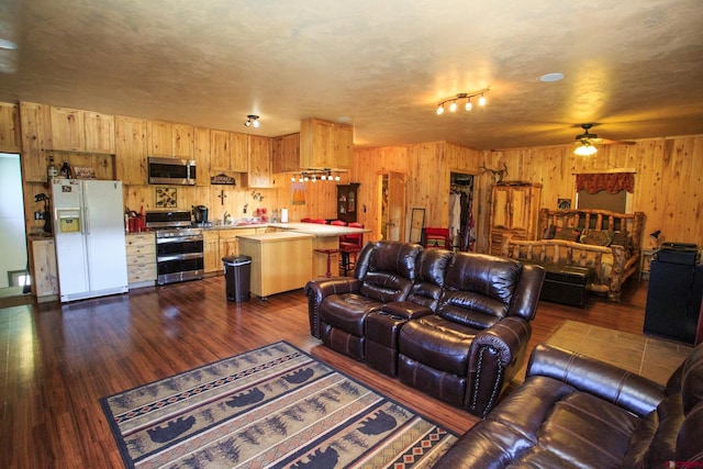 living room with wood walls, sink, ceiling fan, a textured ceiling, and dark hardwood / wood-style flooring