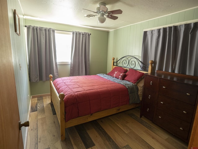 bedroom featuring wood-type flooring, a textured ceiling, ceiling fan, and ornamental molding