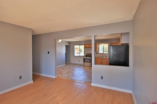 unfurnished living room with a textured ceiling and light hardwood / wood-style flooring