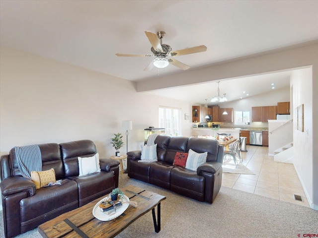 living room with ceiling fan with notable chandelier, plenty of natural light, light tile patterned flooring, and lofted ceiling