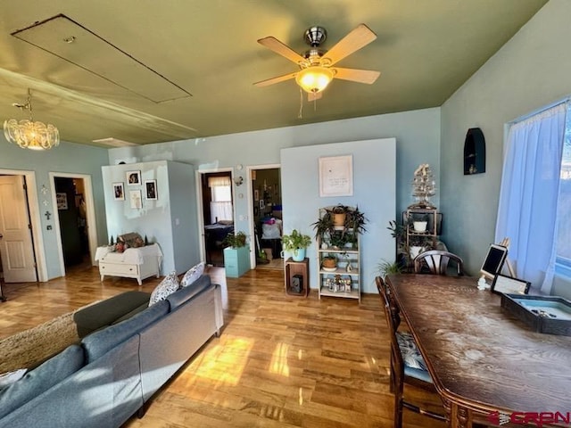 living room featuring ceiling fan with notable chandelier and light wood-type flooring