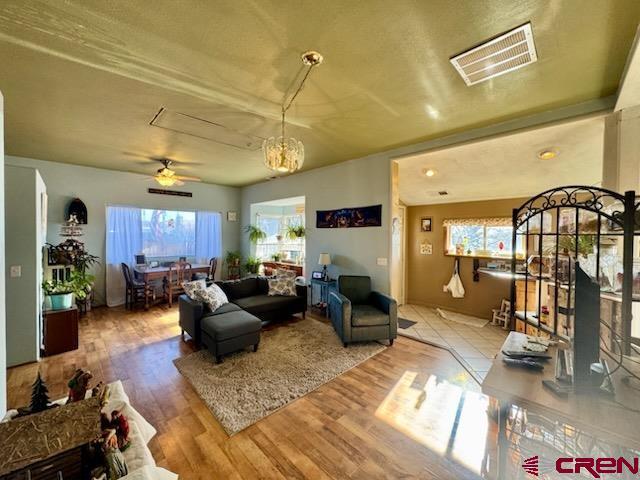 living room featuring a wealth of natural light, ceiling fan with notable chandelier, and hardwood / wood-style flooring