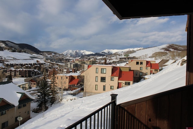 snow covered back of property with a mountain view