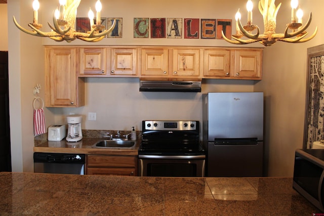 kitchen featuring appliances with stainless steel finishes, exhaust hood, a notable chandelier, and sink