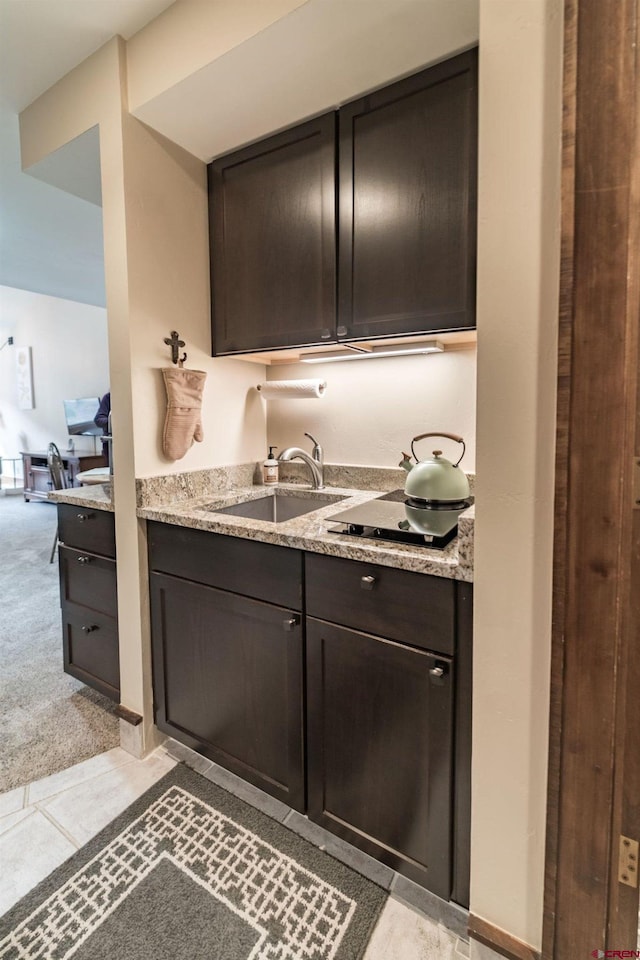 kitchen with light carpet, sink, black cooktop, dark brown cabinets, and light stone counters