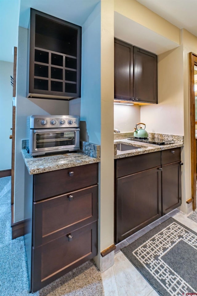 kitchen featuring light stone countertops and dark brown cabinets