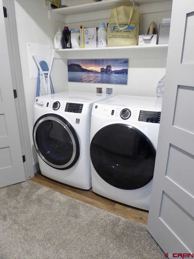 clothes washing area featuring light hardwood / wood-style flooring and washer and clothes dryer