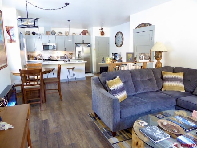 living room with sink, dark wood-type flooring, and a chandelier